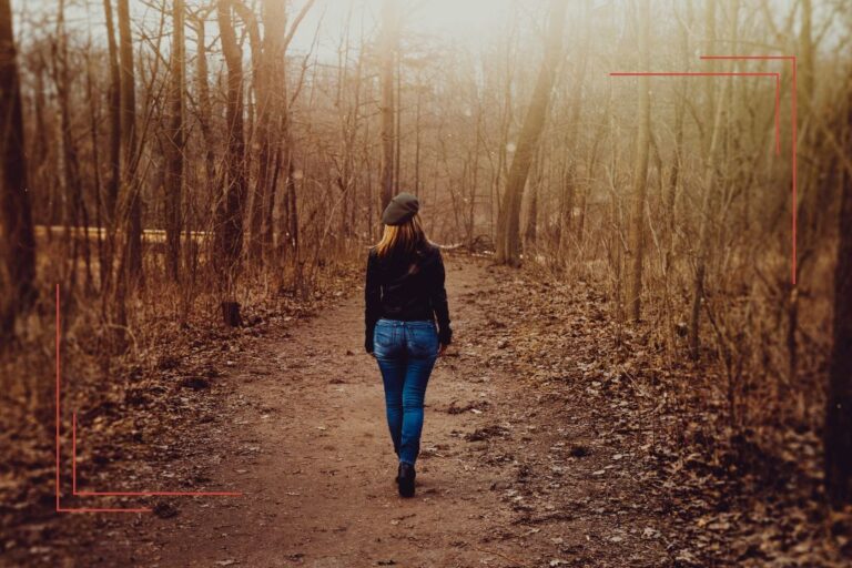 Frau geht allein durch den Wald – Symbol für Erschöpfung bei Schilddrüsenunterfunktion Symptomen