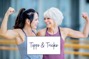 Zwei Frauen nach dem Krafttraining in den Wechseljahren lachen sich an und zeigen ihre Muskeln