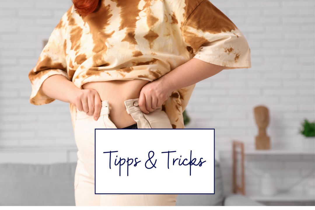 Frau versucht, enge Hose über den Bauch zu schließen – Gewichtszunahme und Bauchfett in den Wechseljahren